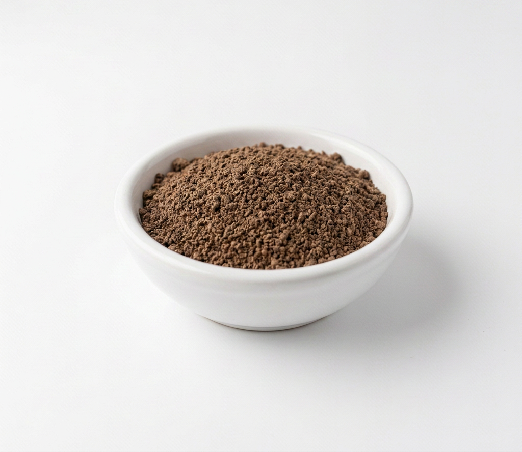 Ceramic bowl containing brown beef liver dust powder with spoon on wooden board